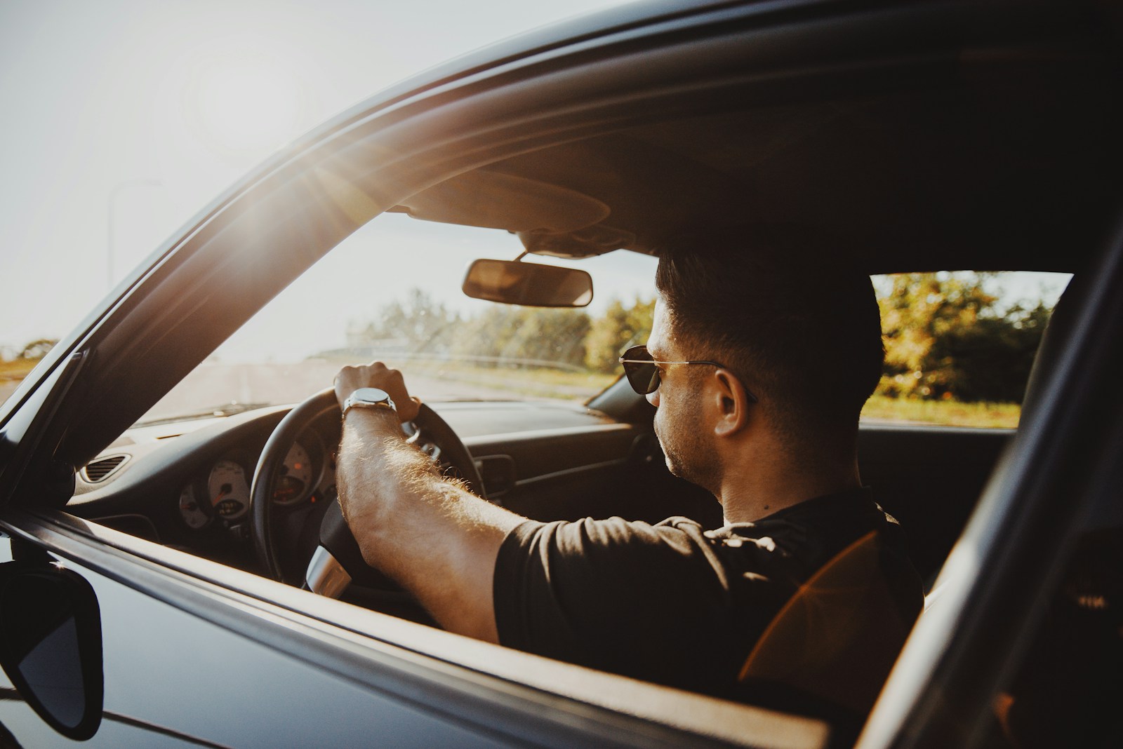 man in black jacket driving car during daytime auto