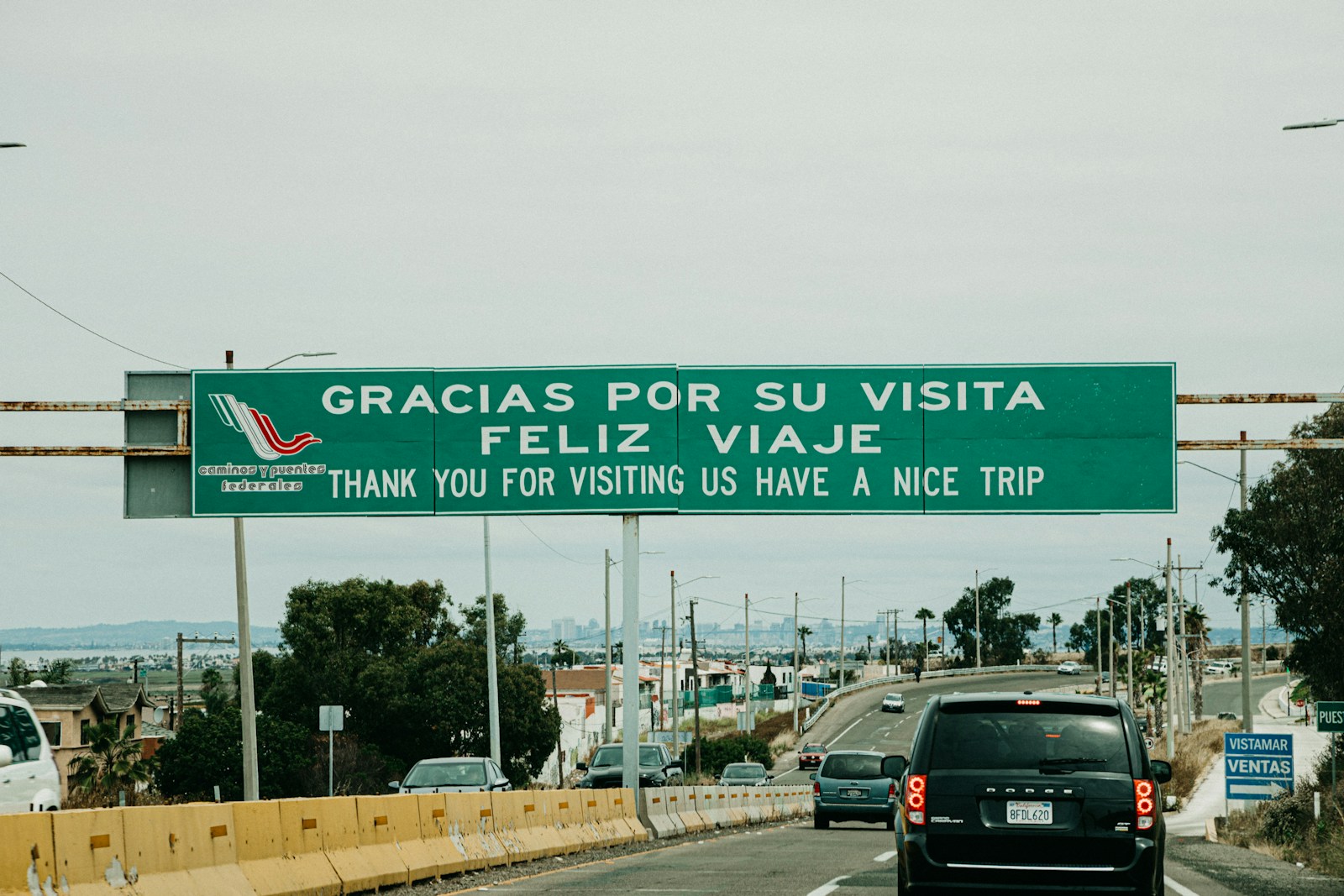 black vehicle on road with gracias por su visita feliz viaje signage, Mexico travel
